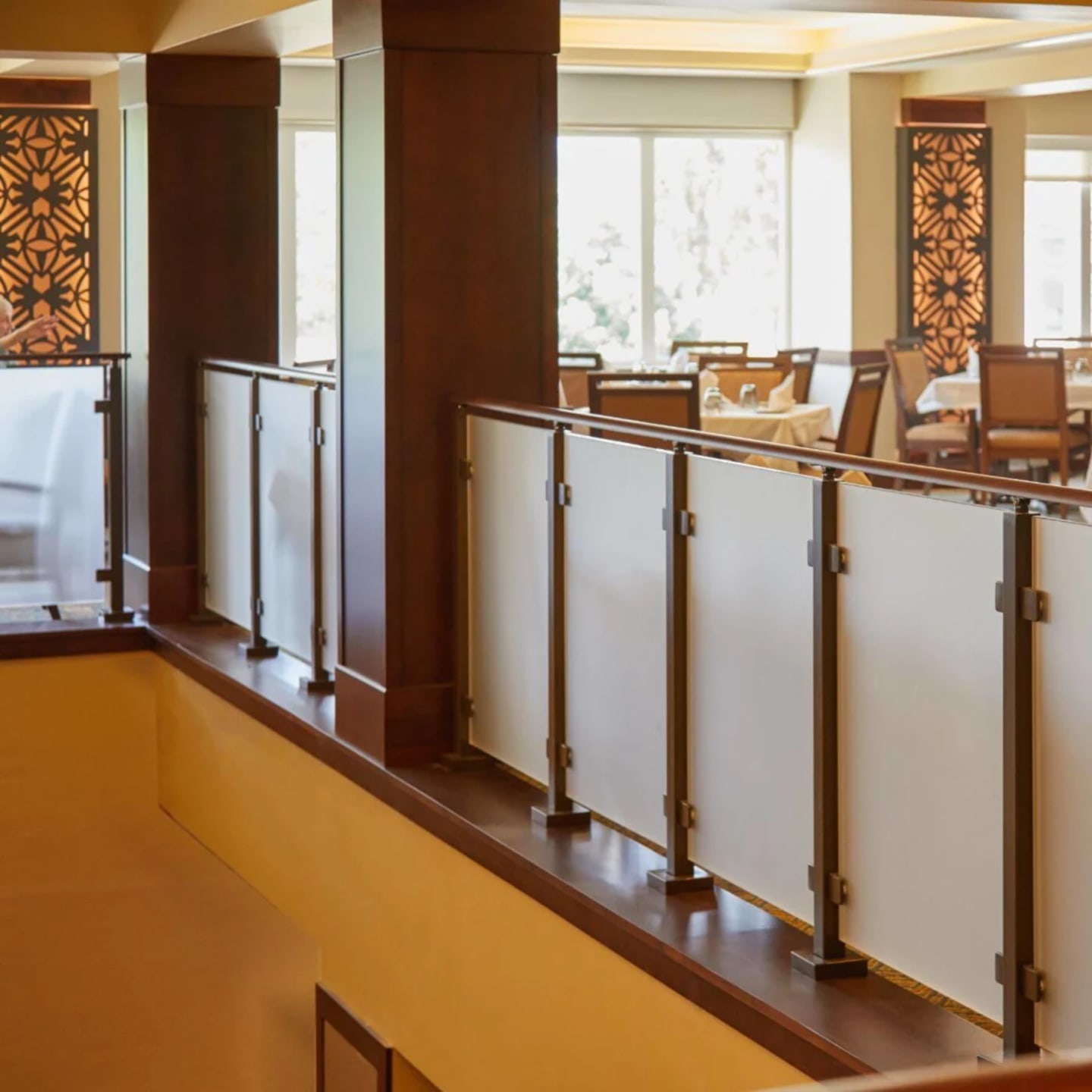 Frosted glass panels set in dark wood balcony framing above a warmly lit dining room