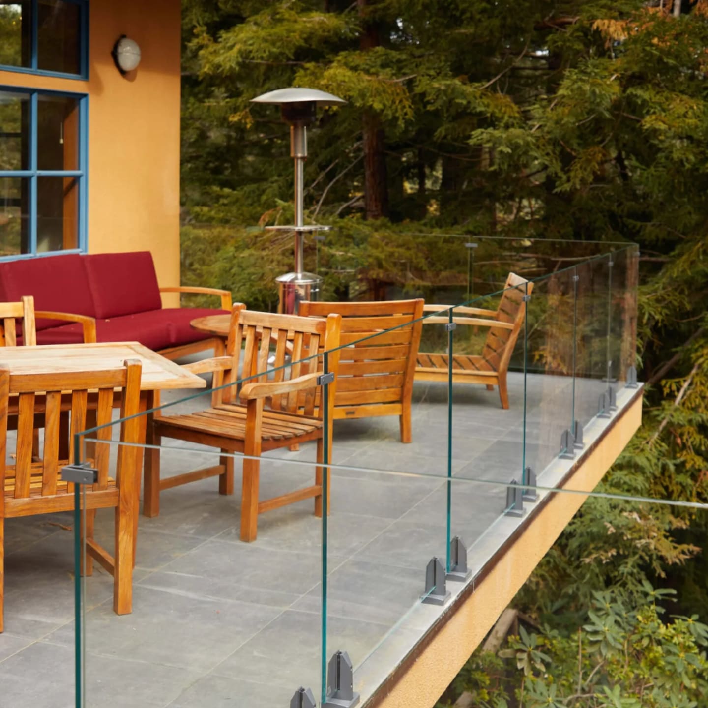Glass railing on base clamps running along the edge of a stone dining terrace