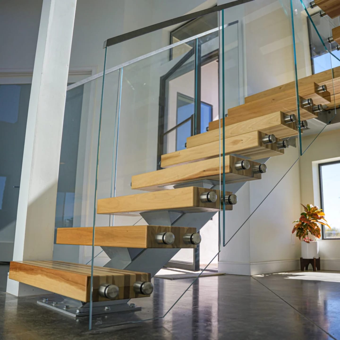 Low angle on glass panels with standoff pins wrapping pale treads over polished concrete