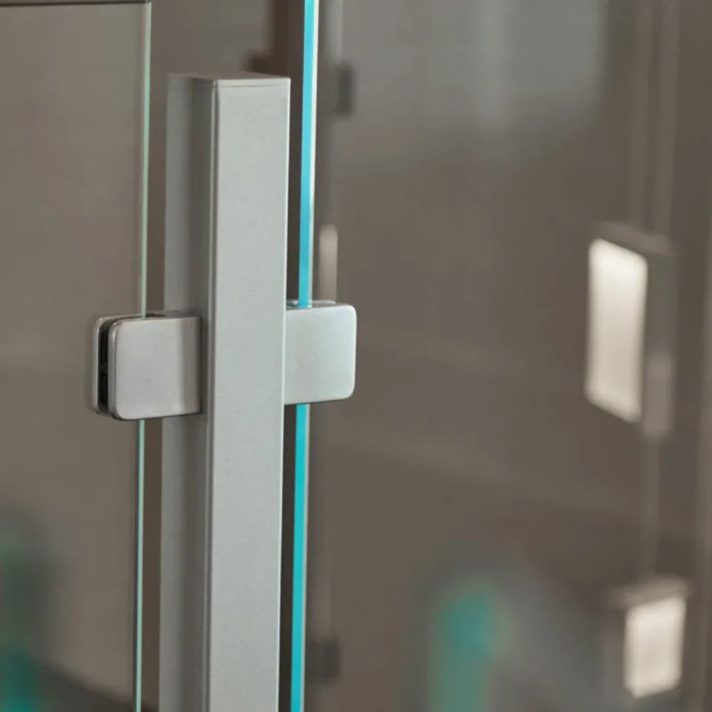 Close view of a brushed metal post clamping a glass panel