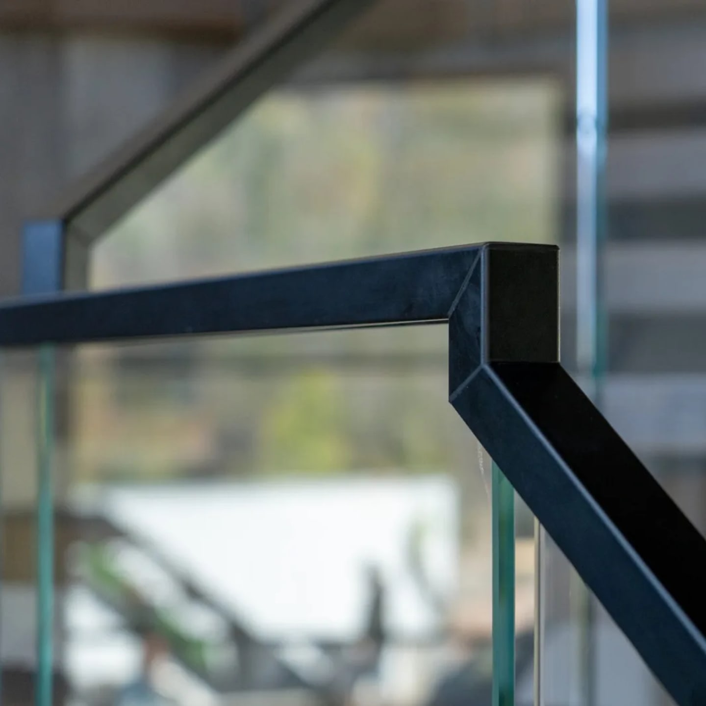 Close view of the mitered black top rail corner capping frameless glass panels