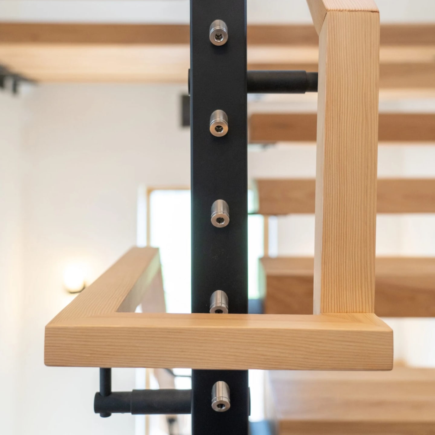 Black post with cable fittings beside a wood handrail and open treads