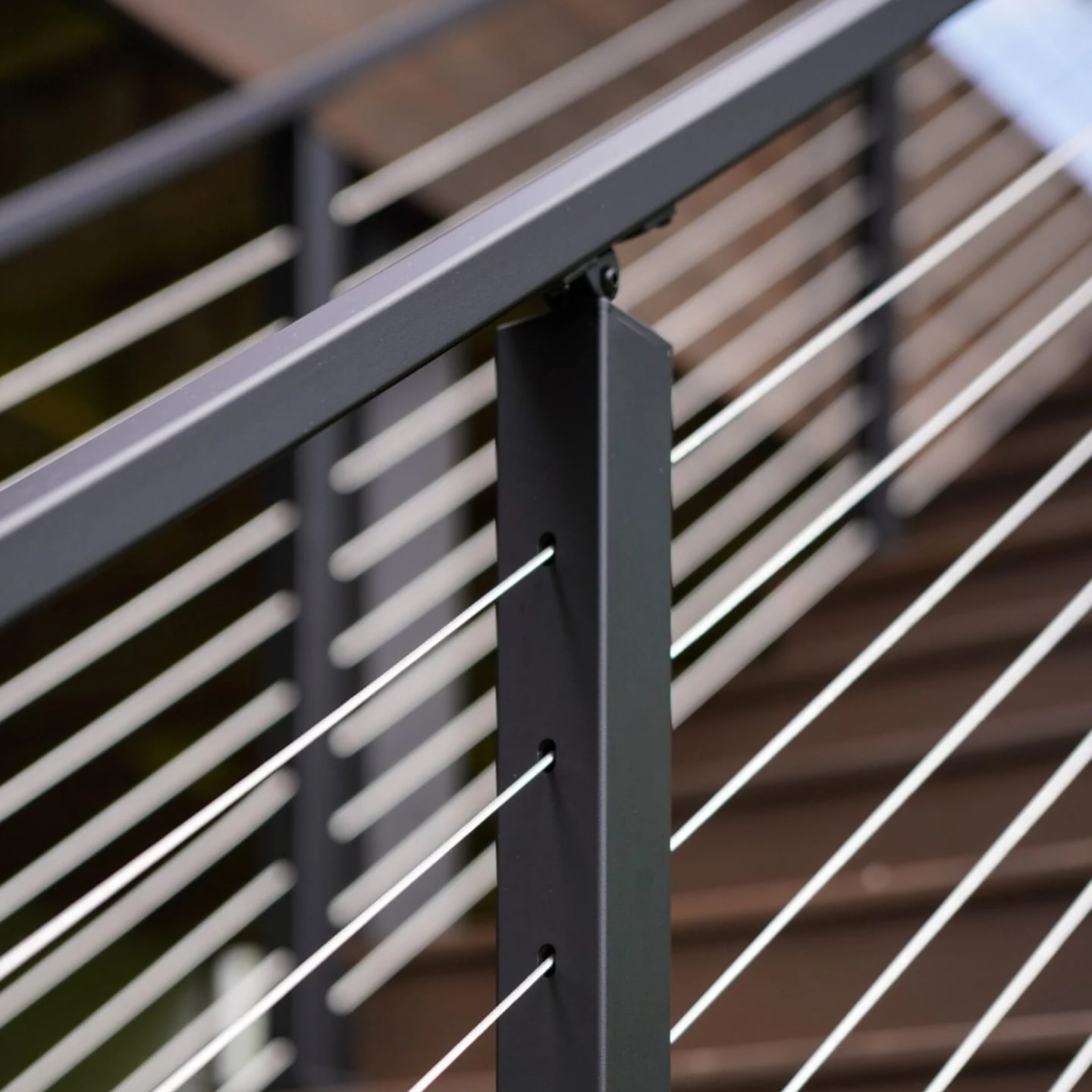 Single post catching light with cable lines running down over deck stairs