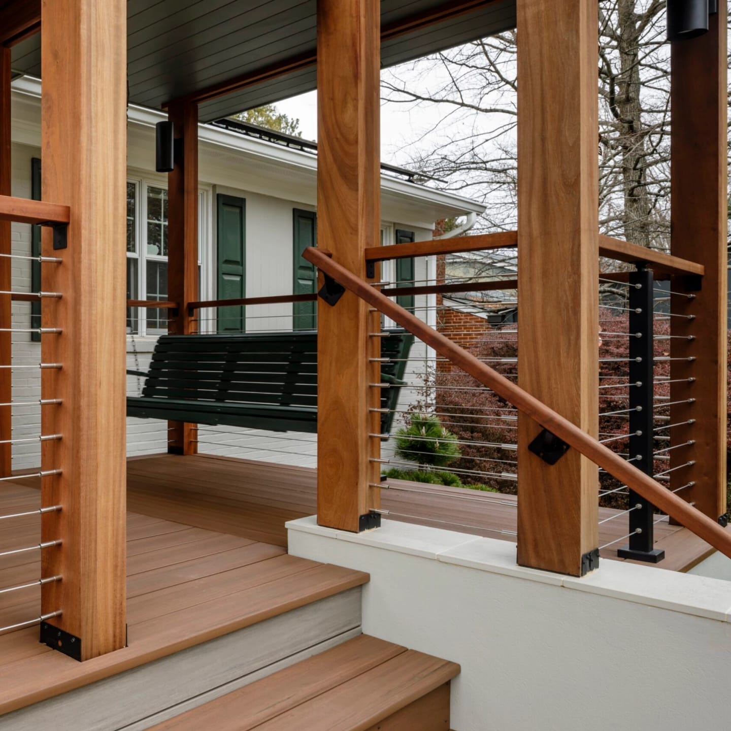 Cable railing frames a porch and its steps between heavy wood posts