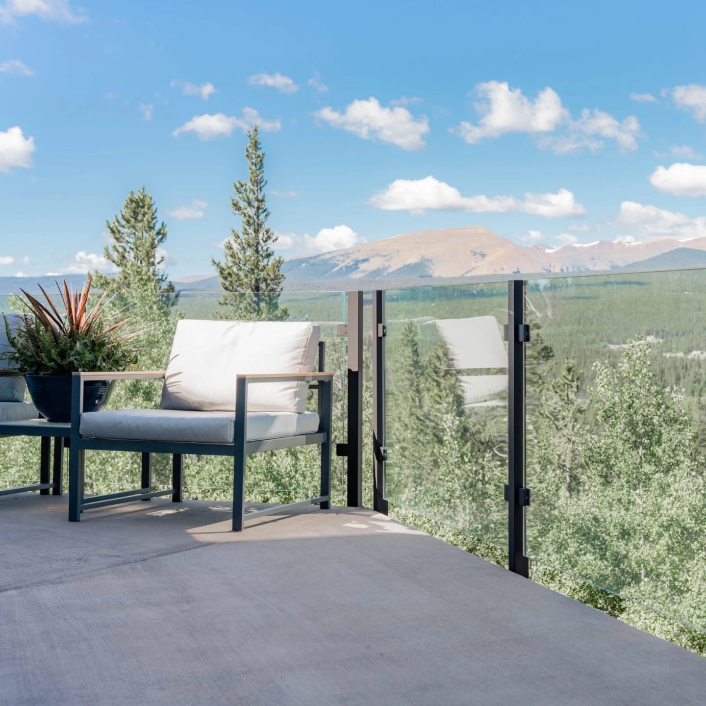Glass panels in black posts open a deck to a wide mountain horizon