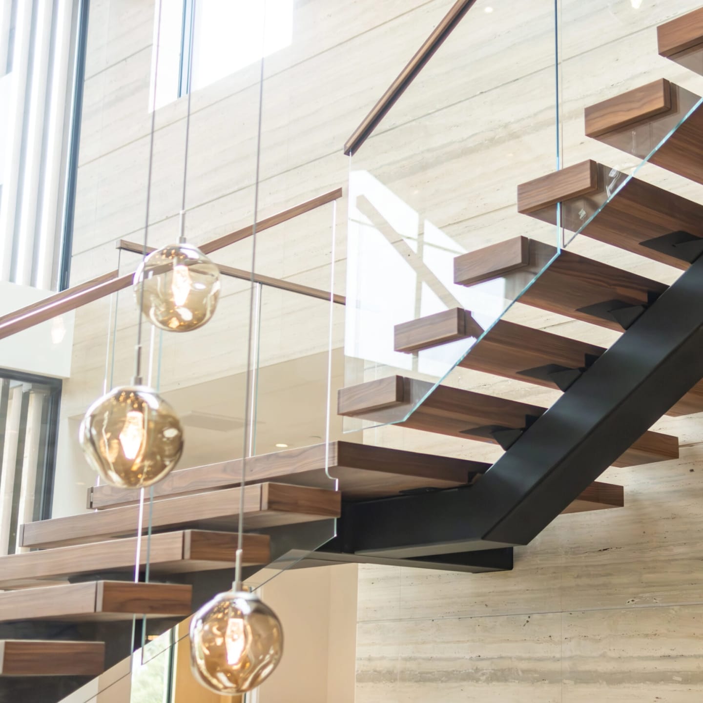 An extra-wide floating stair passes a row of amber globe pendants