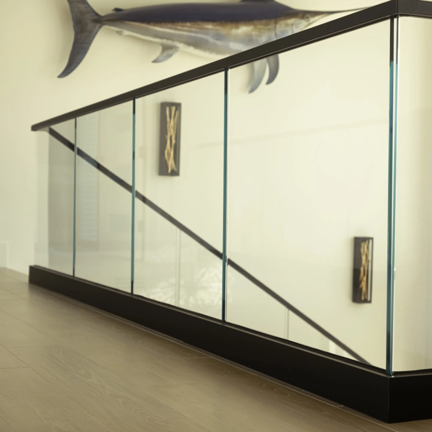 Corner of the glass railing seated in its black base shoe and cap rail