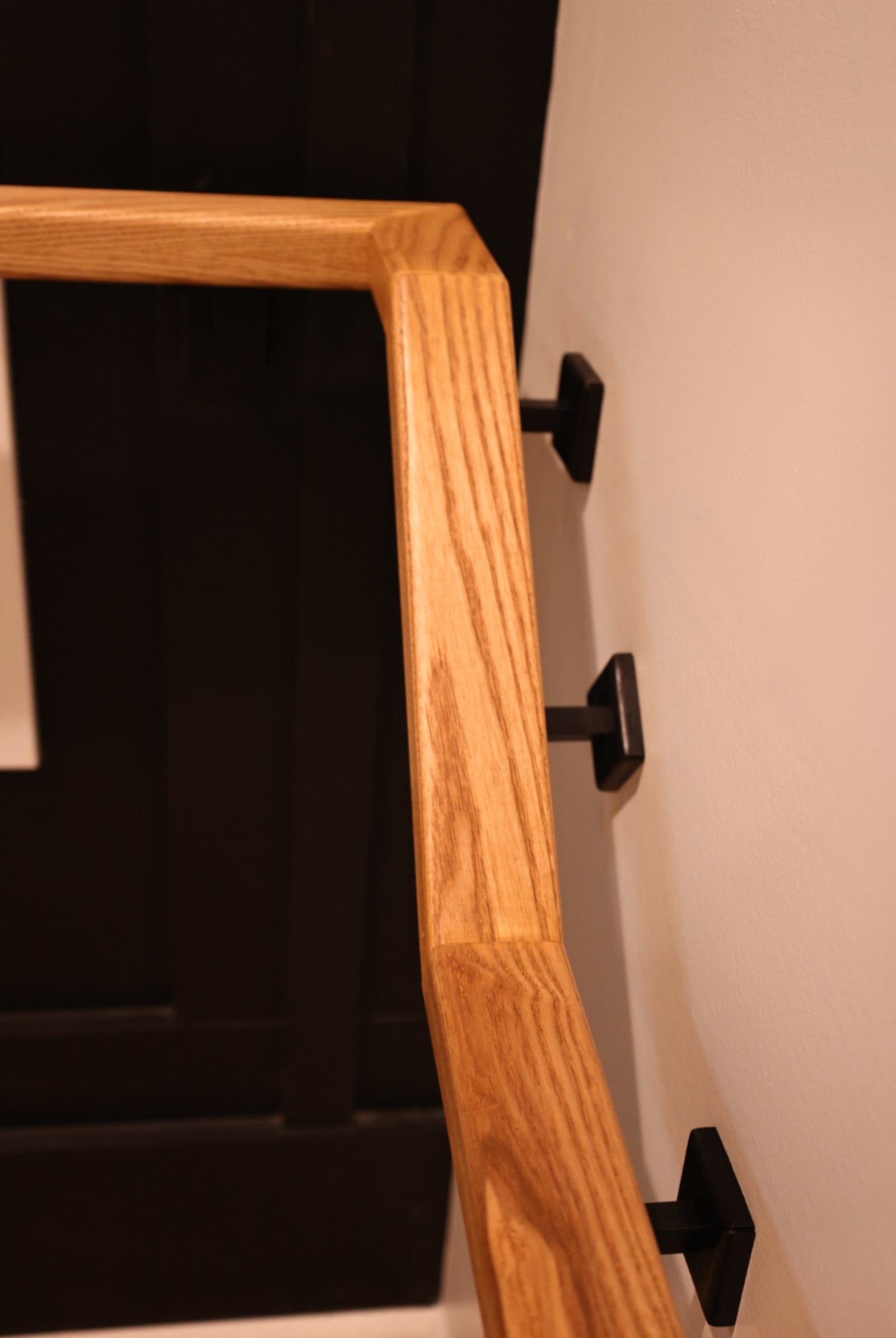 Close view of an ash wall handrail on black square brackets