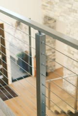 Brushed stainless post and handrail with cable infill above light oak floors.