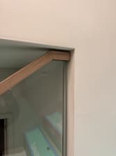 White oak handrail on frameless glass ending cleanly into a wall return