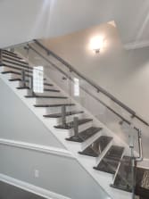 Stainless post-mounted glass railing with a round stainless handrail along a dark-tread commercial stair