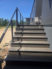 Black cable railing on composite exterior stairs up to a deck
