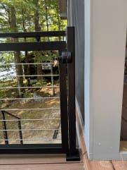 Black aluminum gate with horizontal rod infill at the top of exterior stairs