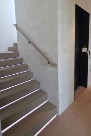 Oak stair with LED-lit treads and wall handrail beside a dark doorway