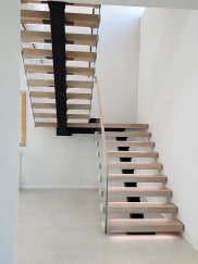 White oak switchback floating stair on a black mono stringer with Vedera glass, wood top cap and LED treads