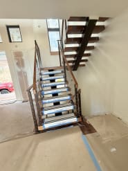 Walnut floating stair on a black mono stringer with cable railing turning at a landing