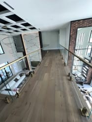 Frameless glass on brass talon spigots lines an oak-floored bridge over a living room