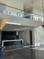 Frameless glass on black talon spigots lines an upper balcony above an open kitchen