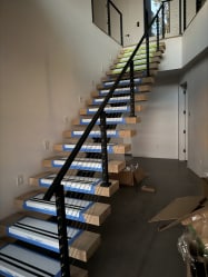 Straight floating oak stair with a black cable railing rising along a white wall