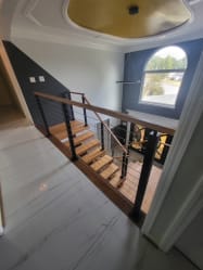 Floating oak stair with black cable railing seen from the upper hallway