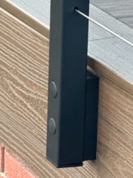 Close-up of a black side-mounted cable post fastened to a composite deck fascia.