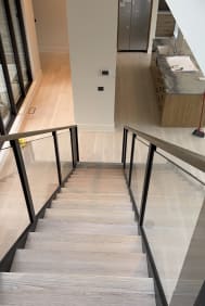 White oak stair framed by frameless glass with walnut handrails on both sides