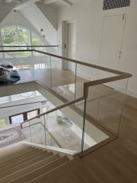 Frameless glass with wood top cap wraps a stair opening overlooking a two-story room