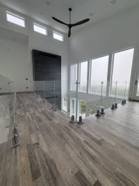 Frameless glass on silver talon spigots lines a loft overlooking tall windows