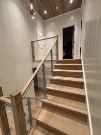 Straight oak stair with aluminum-post glass railing and oak handrail under a wood ceiling