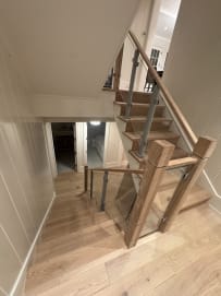 Glass railing on aluminum posts with chunky oak newels and handrail on a turning oak stair