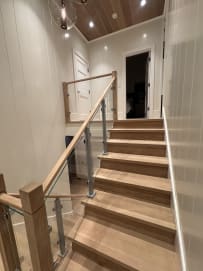 Straight oak stair with aluminum-post glass railing and oak handrail under a wood ceiling