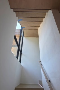 Oak stairs with LED-lit treads and a wall handrail rising toward a window