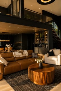 A black FLIGHT Mono with glass railing rises behind a leather sofa in a moody dark-walled great room.
