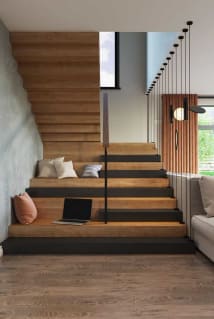 A warm oak Stack stair with built-in seating steps and slender black vertical rods beside a pendant-lit window.