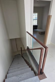 Frameless base rail glass with a walnut cap and squared walnut newel at the head of a stair