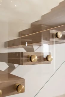 Close-up of brass standoff pins securing glass to the edges of oak floating treads.