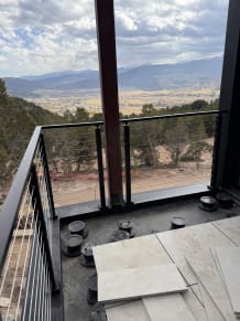 Black cable railing corner on a balcony looking out over a mountain valley