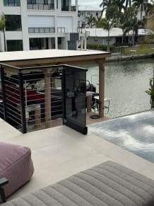 Solar gray glass panel and black cable railing beside a pool overlooking a canal and boathouse