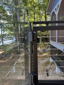 Jet black gate with rod infill meeting frameless glass on a lakeside deck
