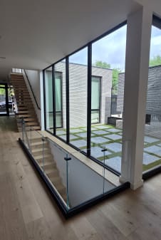 Base rail glass around a stair opening beside a glass wall looking onto a courtyard
