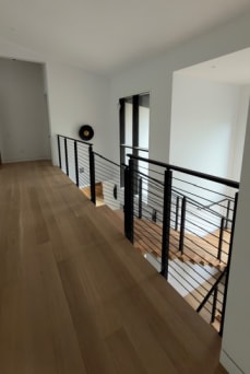 Black rod railing wraps a stair opening on a white oak upper floor
