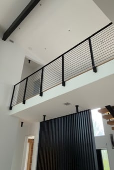 Black rod railing on an interior loft balcony beneath a vaulted ceiling