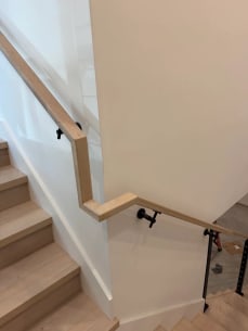 White oak wall handrail wraps a stair turn above a cable railing