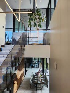 Frameless standoff-pin glass railing along a floating stair above a long dining table