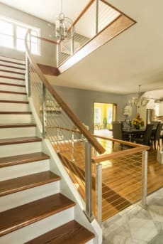 Stainless cable railing with wood handrail along a white-riser stair in a traditional foyer.