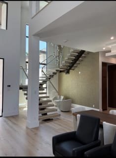 White oak FLIGHT Mono switchback with glass railing and a wood cap in a bright great room