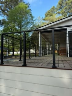 Black horizontal rod railing along a raised deck beside a covered porch.