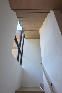 Oak stairs with LED-lit treads and a wall handrail rising toward a window