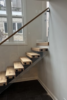 Short white oak floating stair on a mono stringer with frameless glass and wood handrail