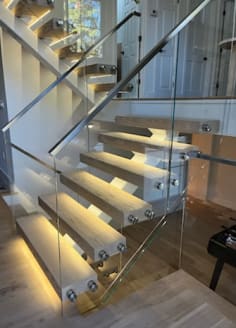 White mono stringer with light oak LED-lit floating treads and frameless glass on stainless standoff pins.